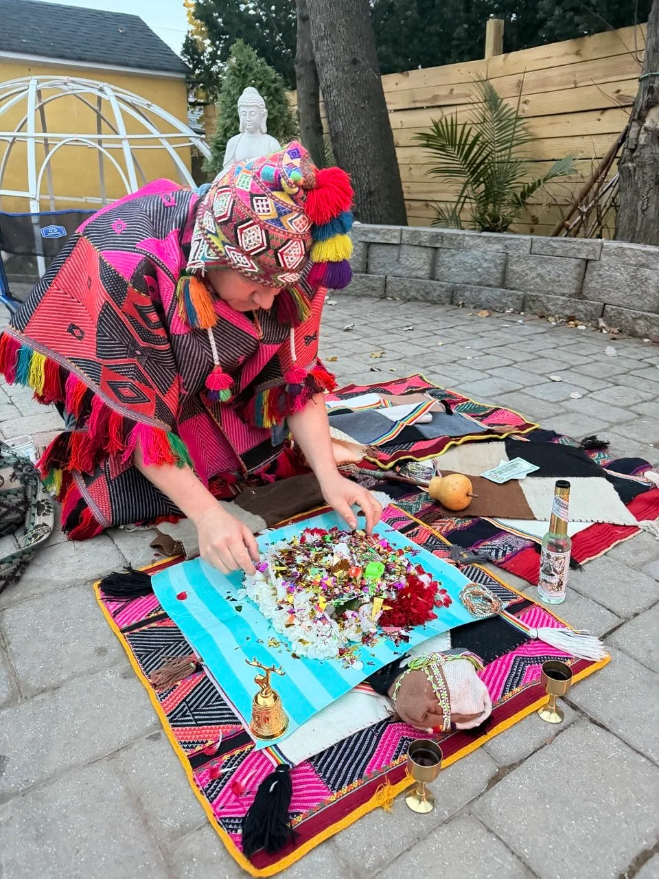 A colorful flower offering being arranged on an Andean woven cloth