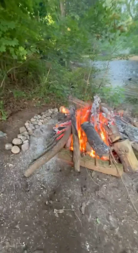 A ceremonial fire surrounded by stones and woodland