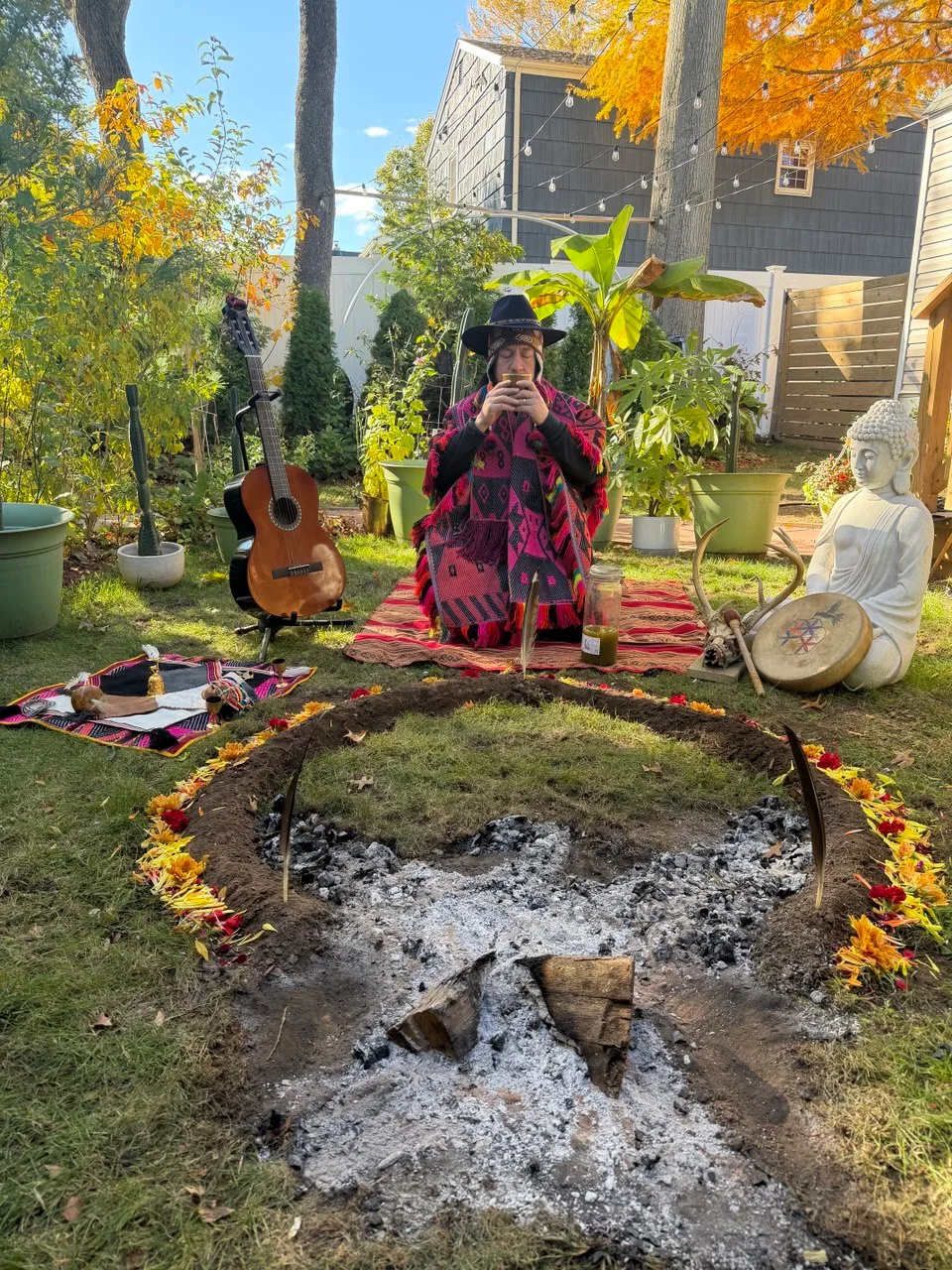 Oswal in a sunlit garden with a guitar, drum, and ceremonial fire circle
